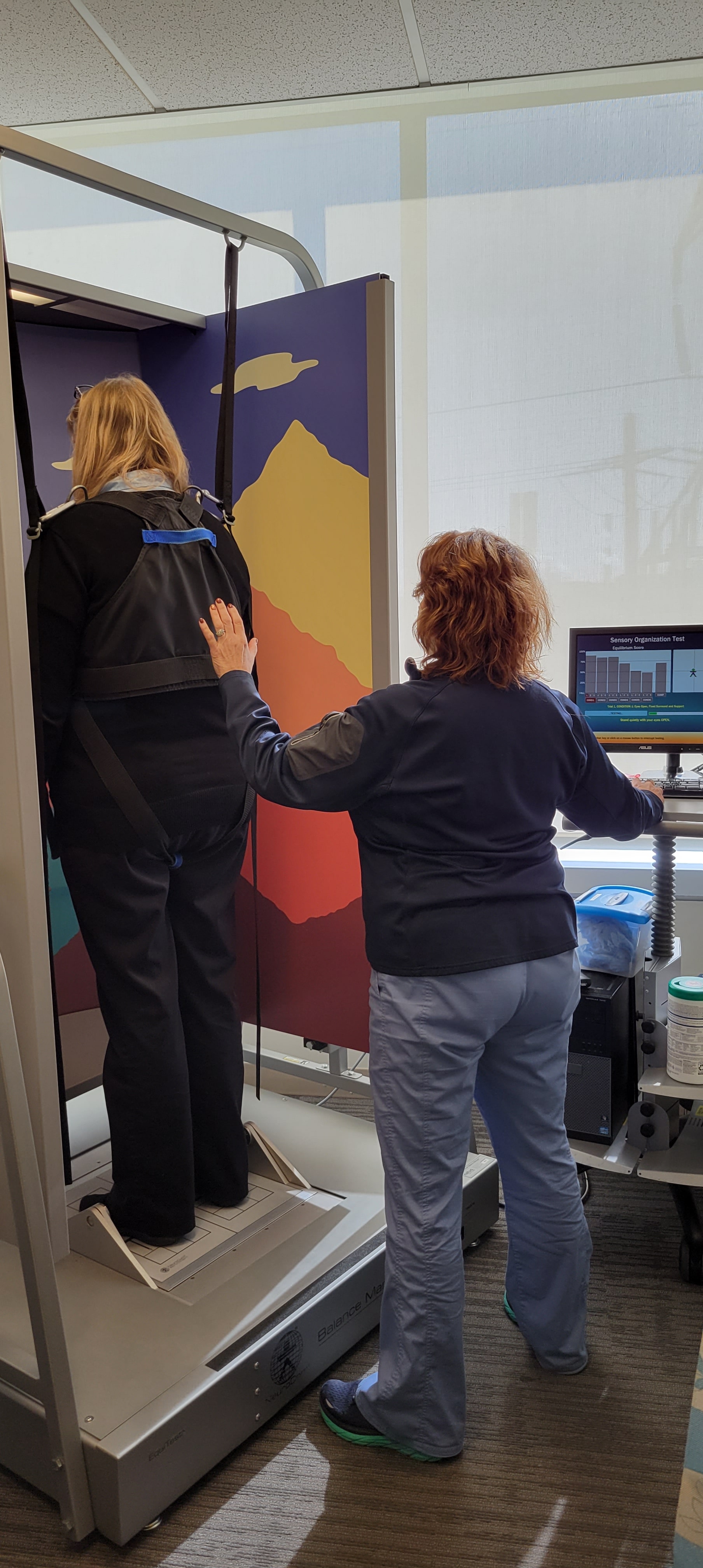 Sherrie Davis demonstrates equipment used at the Penn Balance and Dizziness Center standing up